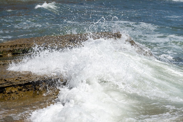 La ola de salpicaduras rueda sobre las rocas del océano