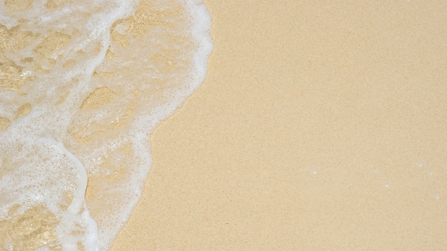 Ola suave del mar en la textura de la playa de arena