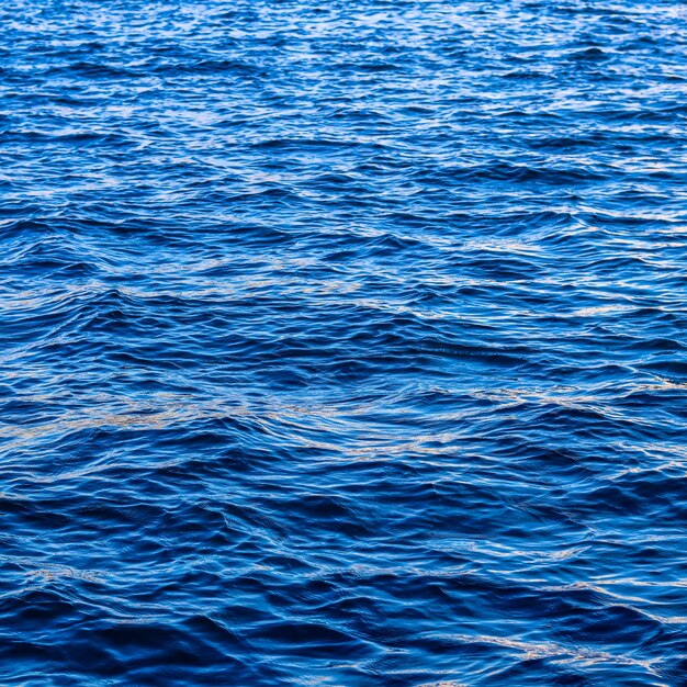 Las olas azules del mar en el resplandor del sol como fondo de la superficie Concepto de vacaciones de verano