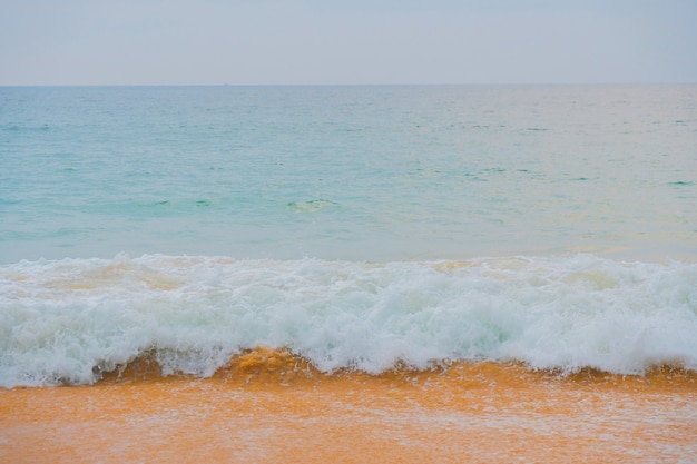 Olas azules del océano y arena amarilla de la playa.