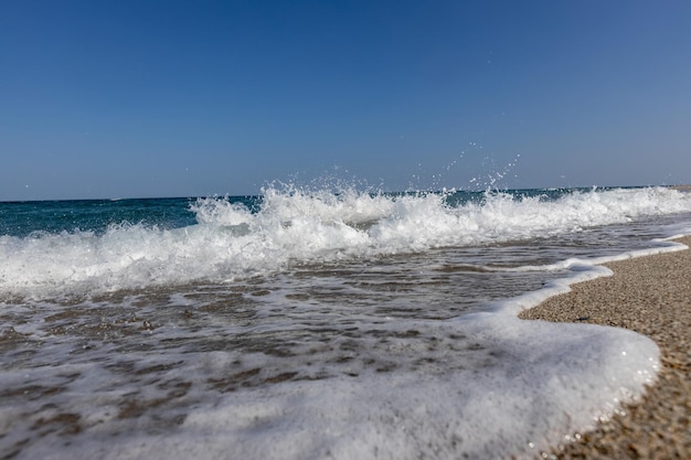 Unas olas blancas en el mar azul en la playa.