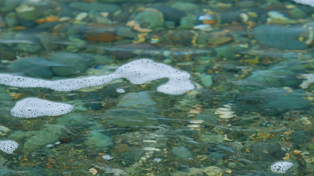 Las olas cerca de la orilla con guijarros y aguas claras piedras de mar en el bokeh de agua