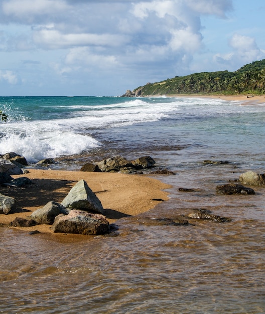 Olas chapoteando contra las rocas en la playa en un día soleado en Puerto Rico