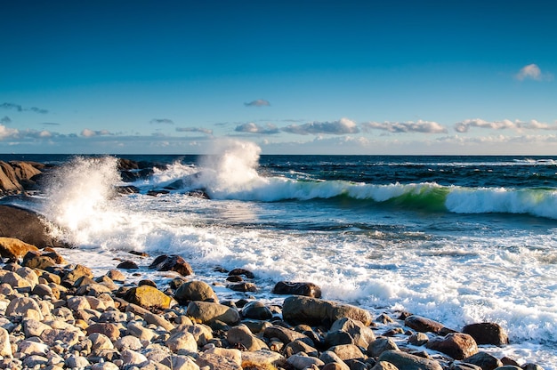 Las olas chapoteando en las rocas en la costa contra el cielo