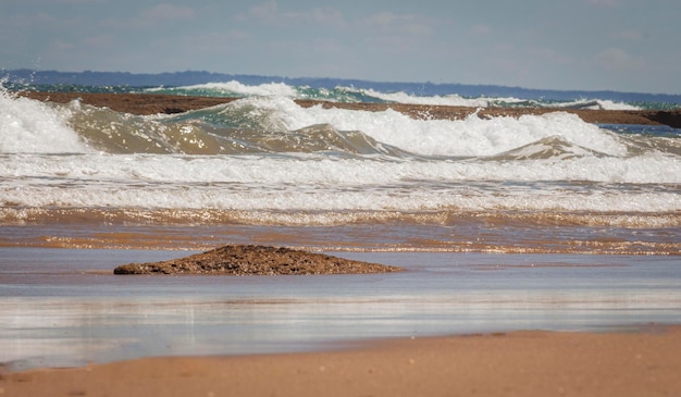 Las olas chocan contra la playa con pequeñas rocas