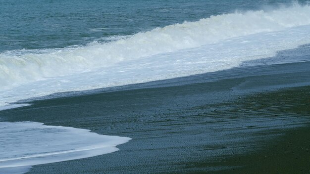 Las olas chocan con las olas oscuras del océano con olas blancas de lavado con textura y aerosol de viento en tiempo real