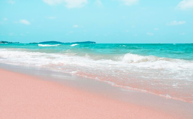 Olas de colores rosa y azul en la playa de arena