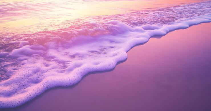 Las olas espumosas se rompen en la arena púrpura al atardecer