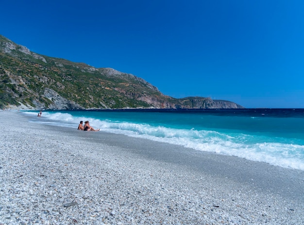 Olas espumosas y turistas bañándose en la playa en el Mar Egeo en Grecia