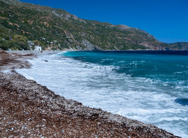 Olas espumosas y turistas bañándose en la playa en el Mar Egeo en Grecia