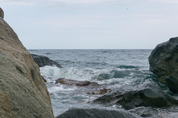 Las olas golpean contra las rocas en la orilla del mar en tiempo nublado