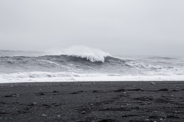 Foto olas en la hermosa playa de arena negra volcánica en islandia.