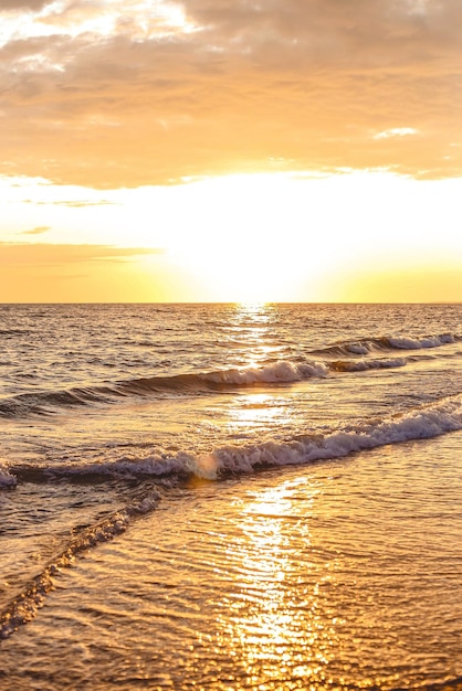 Las olas del mar en la orilla del mar se derraman sobre la arena arenosa por la noche al atardecer