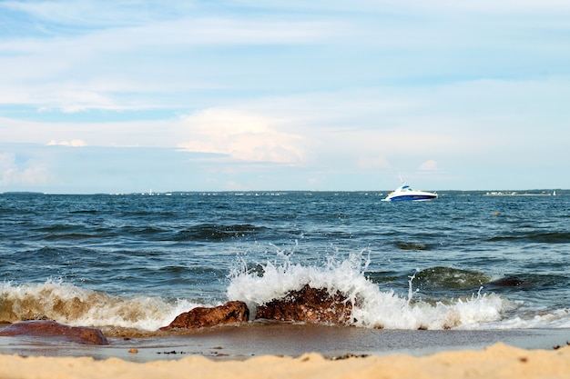 Las olas del mar en las piedras y el barco en el agua azul, el horario de verano del mar Báltico en el paisaje marino de Tallin