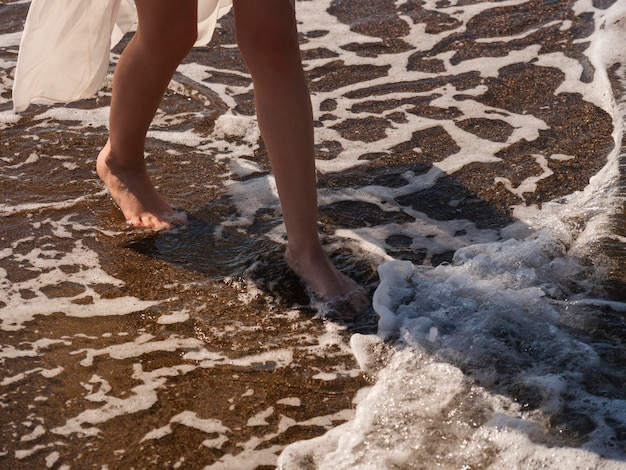 Olas de mar y pies de una mujer que camina