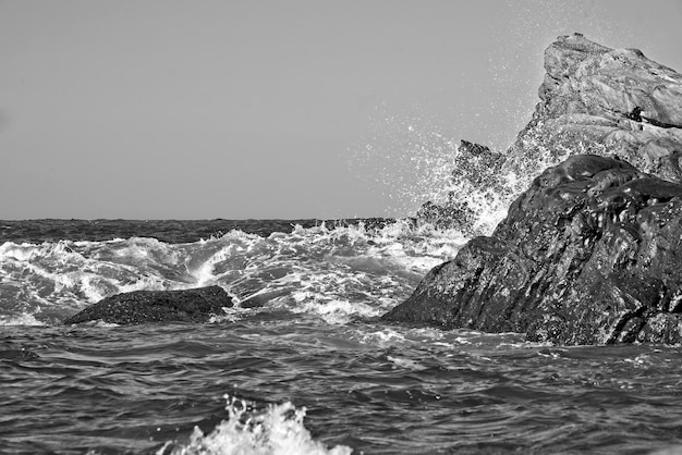 Foto las olas del mar salpican las rocas contra un cielo despejado.