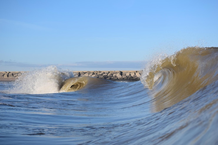 Foto las olas del mar salpicando la orilla contra el cielo despejado