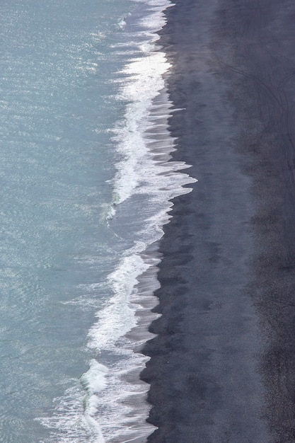 Las olas del océano Atlántico caen sobre la arena negra de la playa de Islandia desde una altura