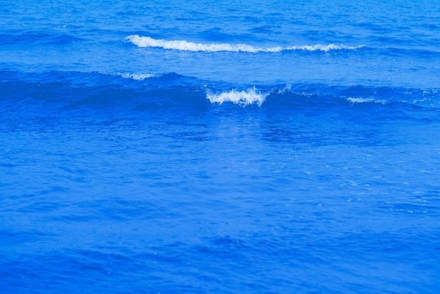 Olas en la playa Ola azul del mar Textura azul de la superficie del agua con ondas salpicaduras y burbujas