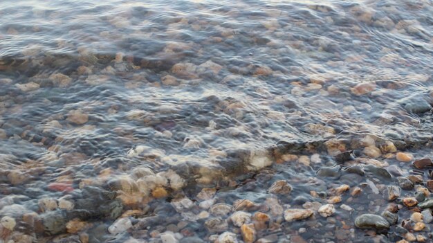 Olas en el río con guijarros de colores en el fondo