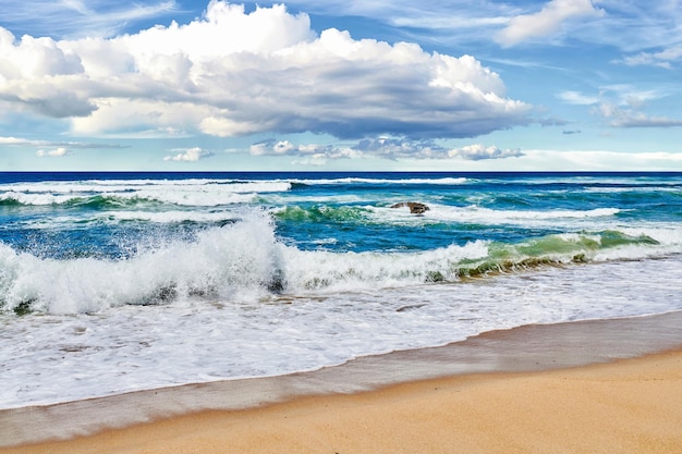 Olas rodando y rompiendo la orilla en la playa durante un día de verano fuera de la corriente oceánica del mar y la marea que se lava en la orilla del mar bajo un cielo azul nublado al aire libre en la naturaleza