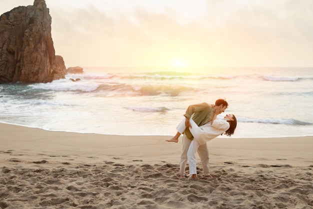 Olas de romance joven pareja romántica bailando en la playa al atardecer disfrutando de la cita cerca de la orilla del océano