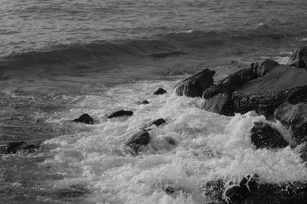 Olas rompiendo en las rocas en blanco y negro