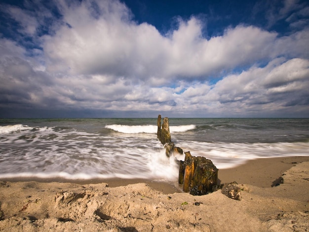 Las olas salpicando en el groyne de madera en el mar contra el cielo