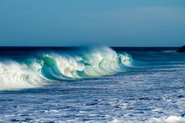 Foto las olas salpicando en el mar contra el cielo despejado