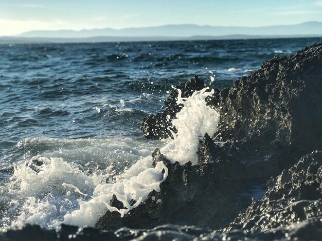 Foto las olas salpicando en la orilla contra el cielo