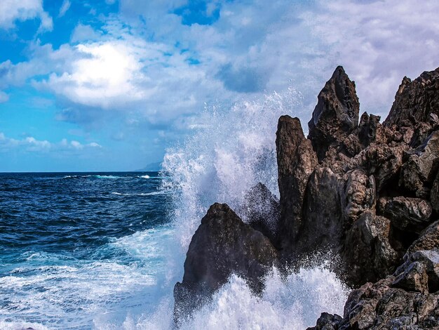 Las olas salpicando las rocas contra el cielo