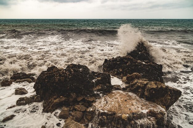 Foto las olas salpicando las rocas en la costa contra el cielo