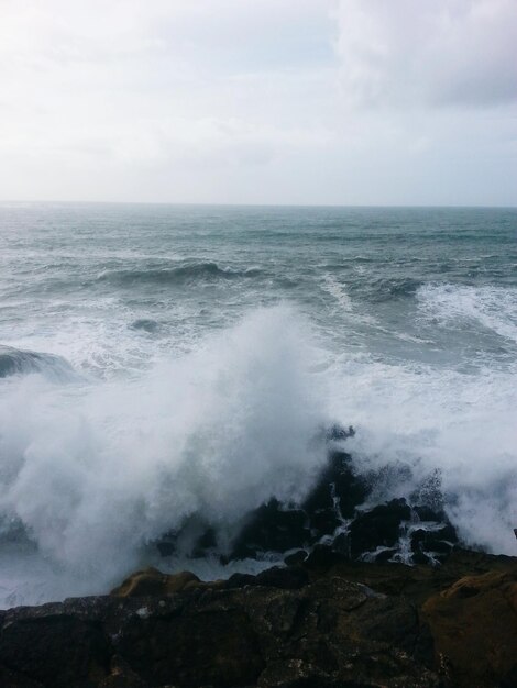 Foto las olas salpicando las rocas en el mar contra el cielo