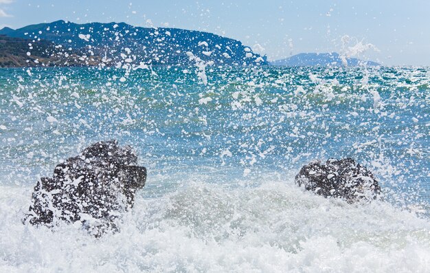 Olas de surf en la costa y el cabo Meganom en el horizonte derecho