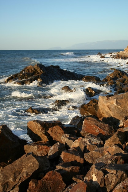 Olas de surf y costa rocosa al amanecer.