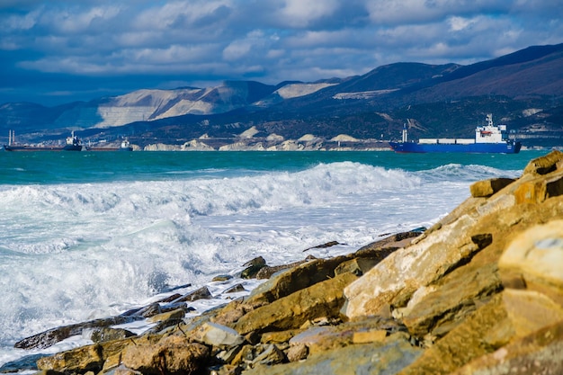 Foto olas de tormenta en espuma blanca se rompen en la playa sembrada de fragmentos de rocas areniscas amarillentas