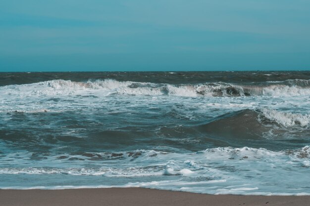 Olas de tormenta oceánicas chocando dramáticamente salpicando Línea del horizonte del cielo Borde de agua de mar naturaleza vista frontal diseño de papel tapiz marino Mal clima nublado nublado Tono azul turquesa verde oscuro mate pálido