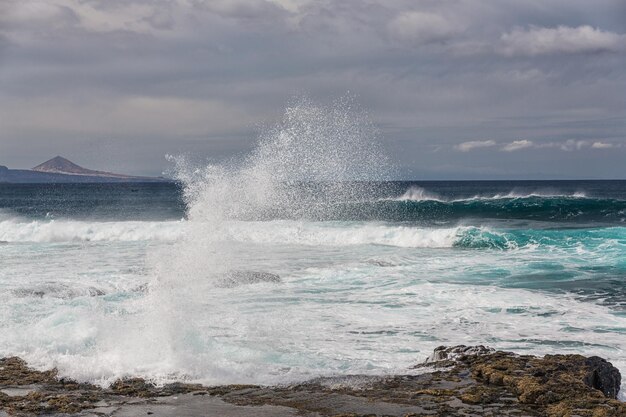 Las olas turbulentas del océano con espuma blanca golpean las piedras costeras