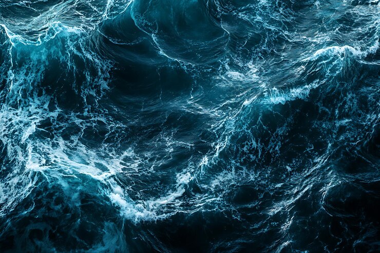 Las olas turquesas del océano con espuma blanca en el fondo de agua oscura