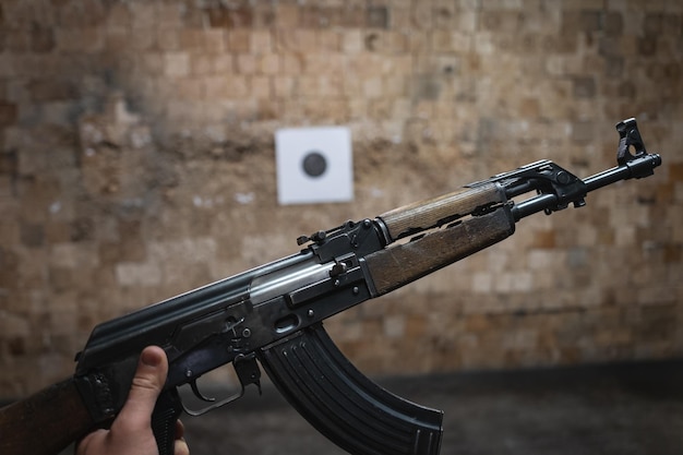 Old ak 47 na mão de um homem em um campo de tiro closeup foto Foto de alta qualidade