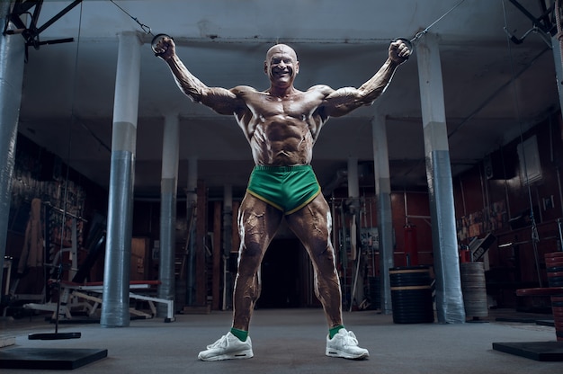 Old Fashion Athlet Bodybuilder macht Armübungen im Fitnessstudio. Brutaler kahlköpfiger kaukasischer Sportlerstil der 80er Jahre. Sport-, Fitness- und Workout-Konzept der 80er Jahre