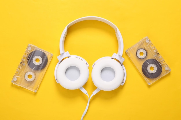 Oldschool Auriculares estéreo con casete de audio sobre fondo amarillo Retro 80s bodegón Vista superior
