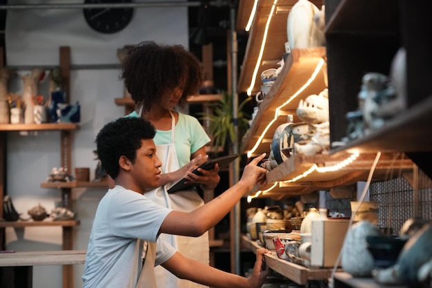 Oleiro de mão jovem afro fazendo vaso de barro na oficina de cerâmica, empresário.