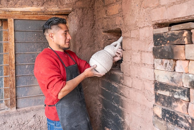 Oleiro latino colocando um vaso que ele acabou de criar em um forno de barro