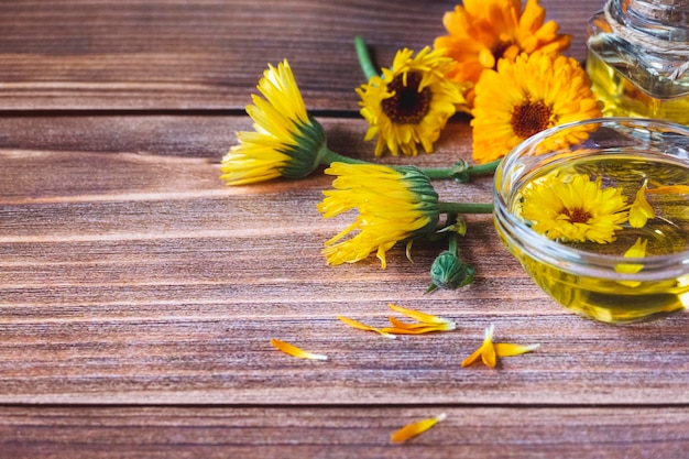 Óleo de calêndula com infusão de ervas feito de flores de calendula officinalis no espaço de cópia de fundo de madeira