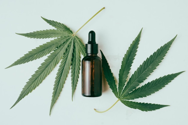 Óleo de cannabis no frasco conta-gotas com folhas verdes sobre fundo branco Conceito de medicina alternativa