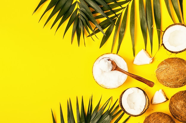 Óleo de coco e coco em um fundo com folhas tropicais