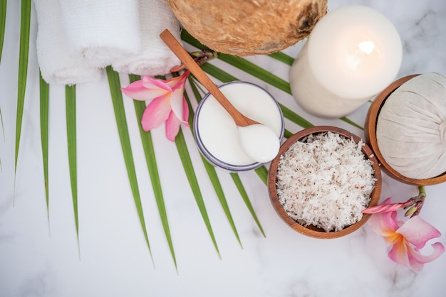 Óleo de coco, folhas tropicais e cocos frescos. Produtos de coco spa na superfície de madeira clara.