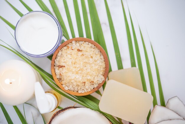 Óleo de coco, folhas tropicais e cocos frescos. produtos de coco spa na superfície de madeira clara.