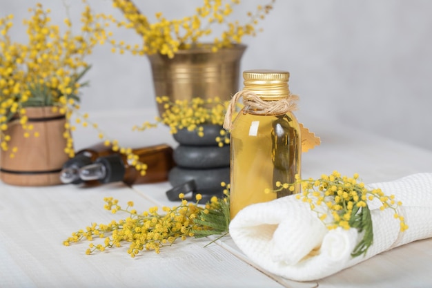 Óleo de massagem de flores de mimosa em frasco de vidro. Fechar-se